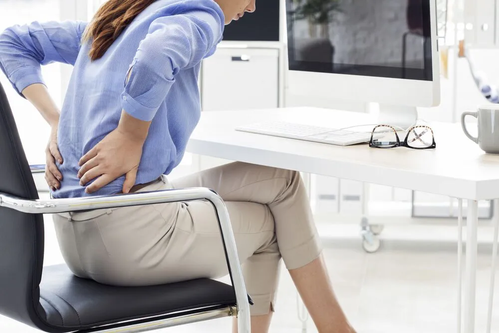 Lady in office chair with back pain